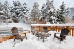 Snowy day with firepit and deck chairs near the hot tub